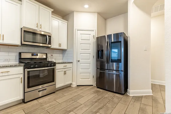 a kitchen with stainless steel appliances and wooden floor