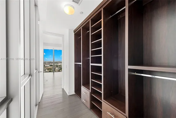 a view of walk in closet with clothes and shoes