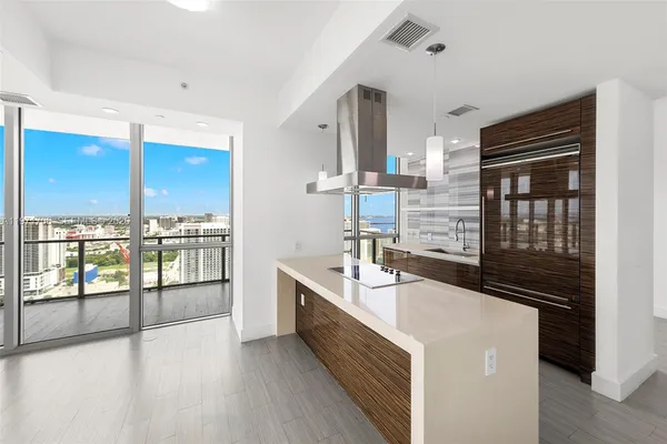 a view of a kitchen with kitchen island wooden floors stainless steel appliances and windows
