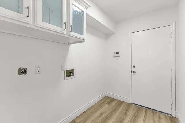 a view of kitchen with stainless steel appliances granite countertop a stove a sink a refrigerator and white cabinets with wooden floor