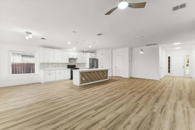 a big room with wooden floor and kitchen view