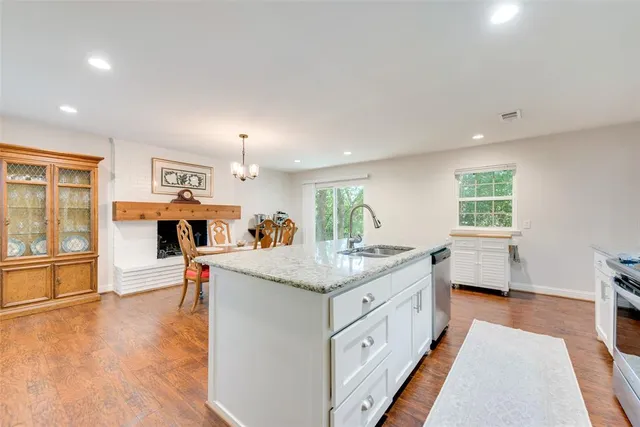 a dining hall with stainless steel appliances granite countertop a stove and a wooden floors