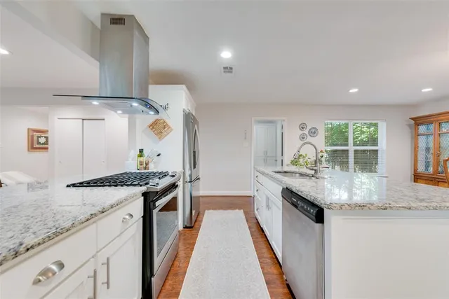 a large white kitchen with stainless steel appliances granite countertop a large window and a sink