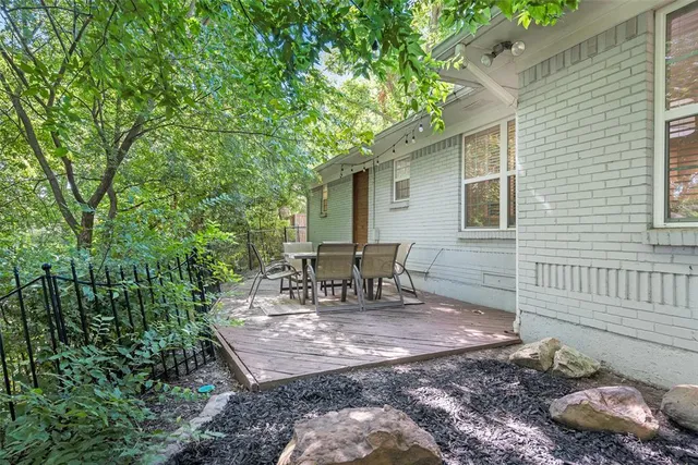 a view of a backyard with table and chairs and a barbeque with large trees
