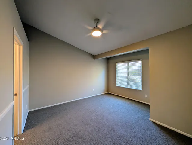 an empty room with a ceiling fan and window