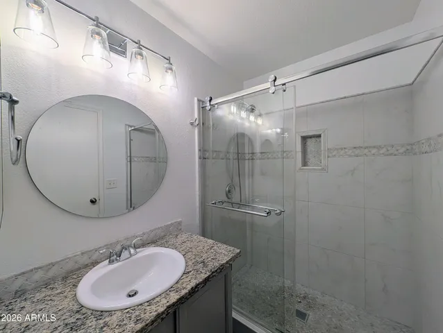 a bathroom with a sink shower and a mirror