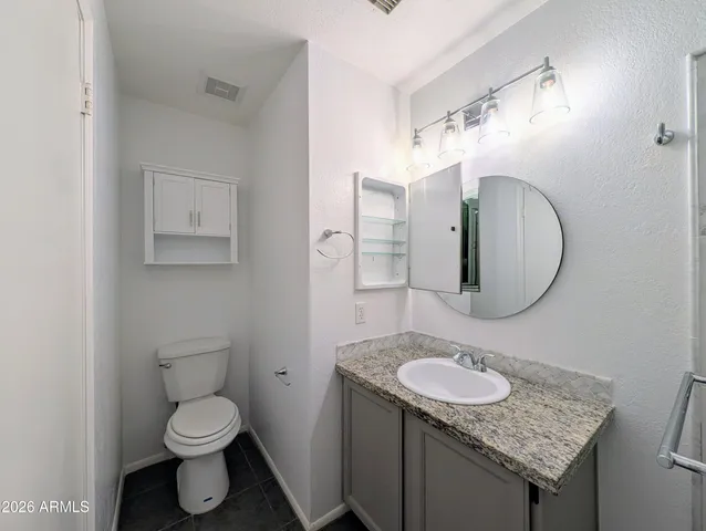 a bathroom with a granite countertop toilet sink and mirror