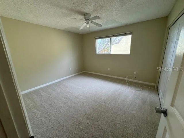 an empty room with windows and fan