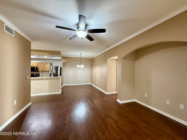 a view of a hallway with wooden floor and a kitchen