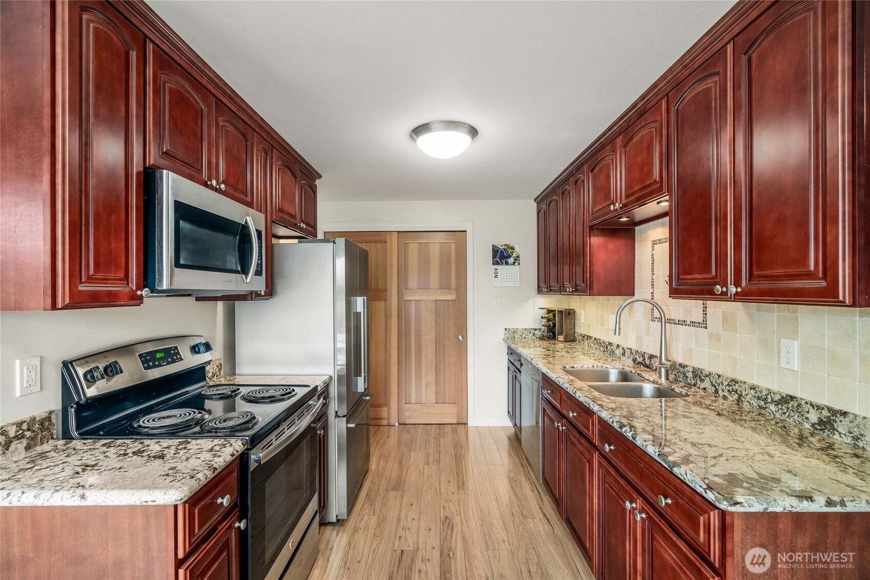1020 5th Avenue South, Unit 8 Edmonds, WA 98020 - Photo 15 of 28 a kitchen with stainless steel appliances granite countertop a stove a sink dishwasher a refrigerator and a microwave oven with wooden floor