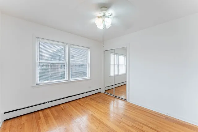 a view of an empty room with a window and wooden floor