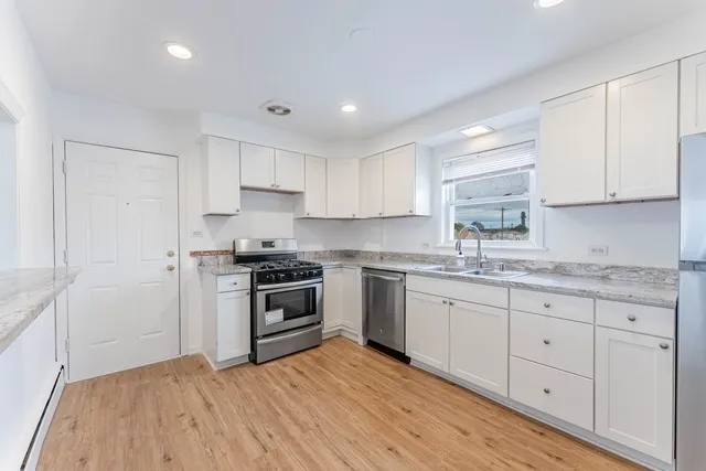 a kitchen with granite countertop white cabinets and stainless steel appliances