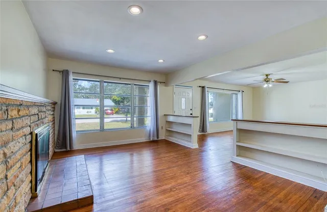 a view of an empty room with wooden floor and a kitchen