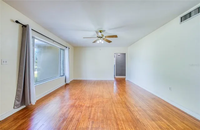 a view of empty room with wooden floor and fan