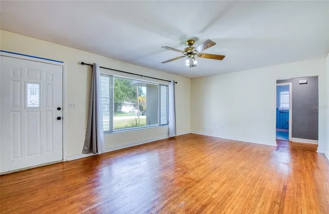 a view of empty room with wooden floor and fan