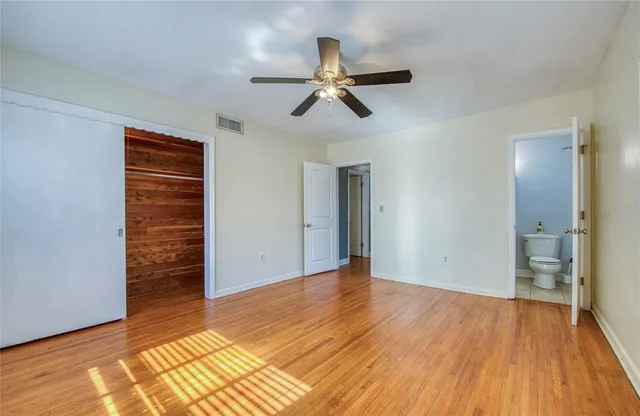 a view of an empty room with window and wooden floor