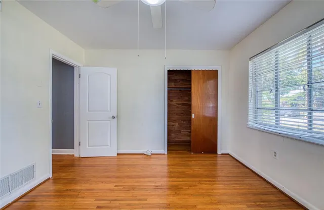 a view of empty room with wooden floor and fan