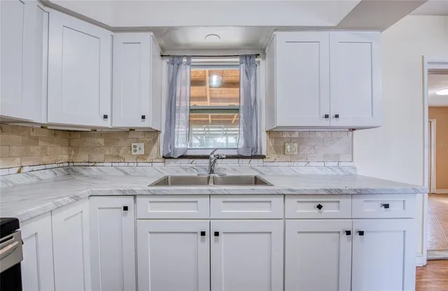 a kitchen with granite countertop white cabinets sink and stainless steel appliances