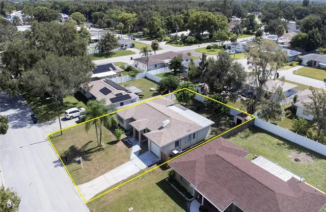 an aerial view of a house with swimming pool and large trees