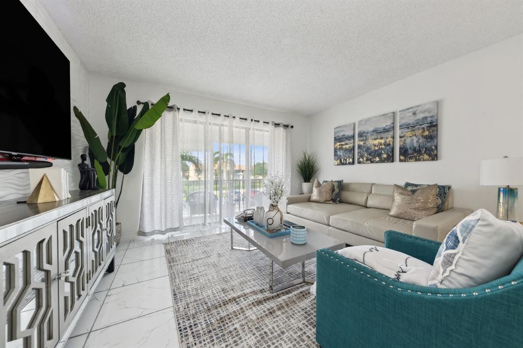608 Sea Pine Way, Unit D2 Greenacres, FL 33415 - Photo 1 of 13 a living room with furniture a flat screen tv and a large window