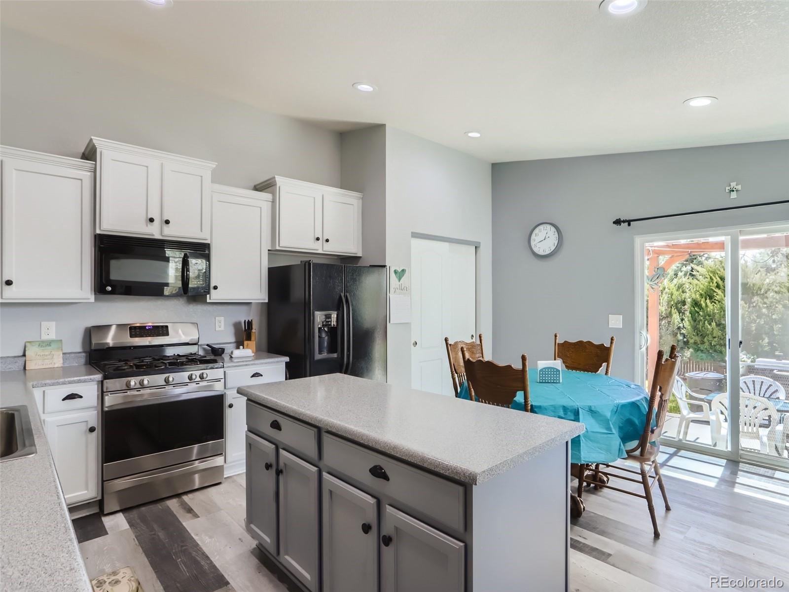 8080 Raspberry Drive Frederick, CO 80504 - Photo 8 of 29 a kitchen with stainless steel appliances a stove a sink a microwave a refrigerator and white cabinets with wooden floor