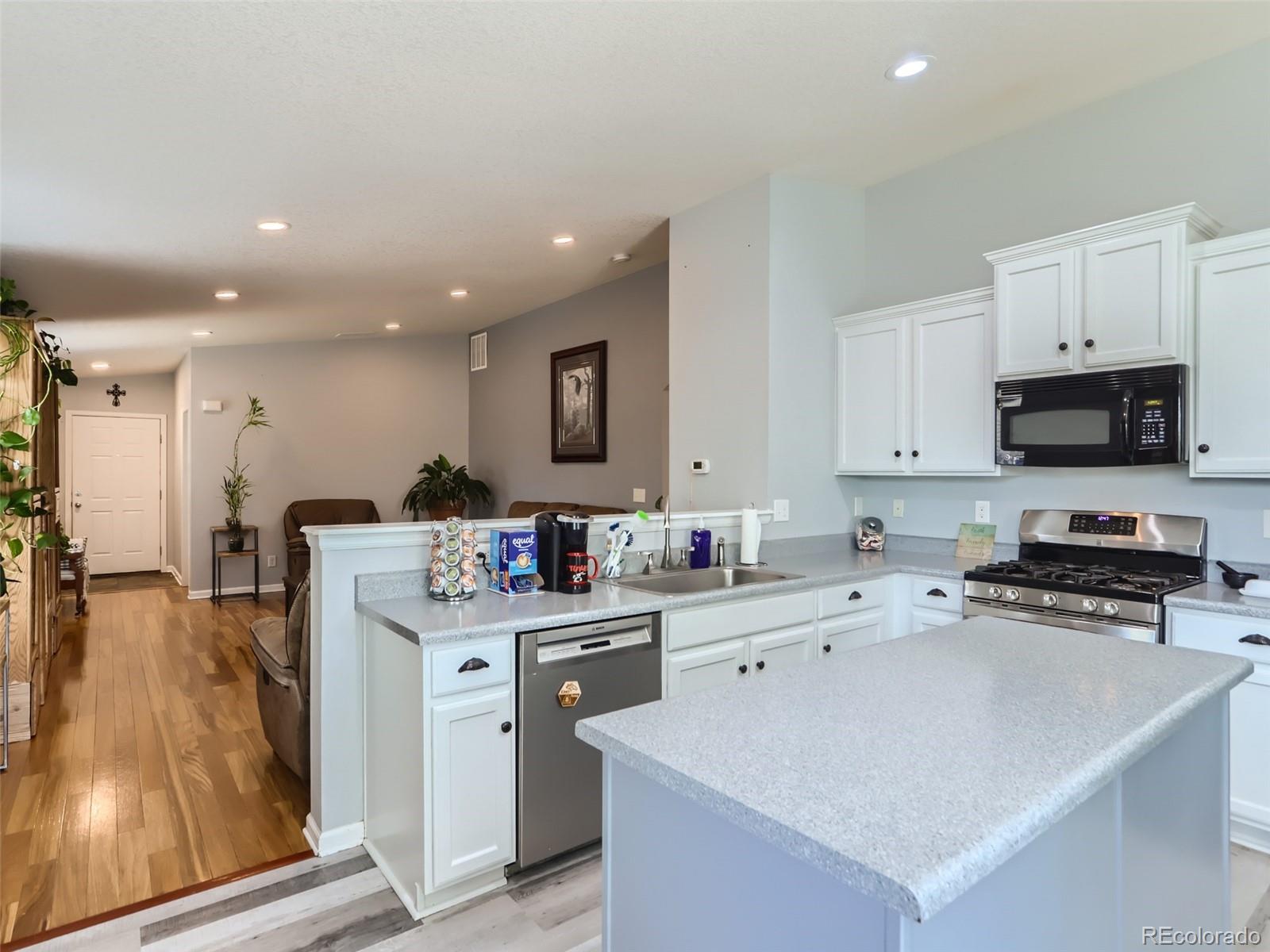 8080 Raspberry Drive Frederick, CO 80504 - Photo 9 of 29 a kitchen with stainless steel appliances a sink a stove a microwave a center island and cabinets