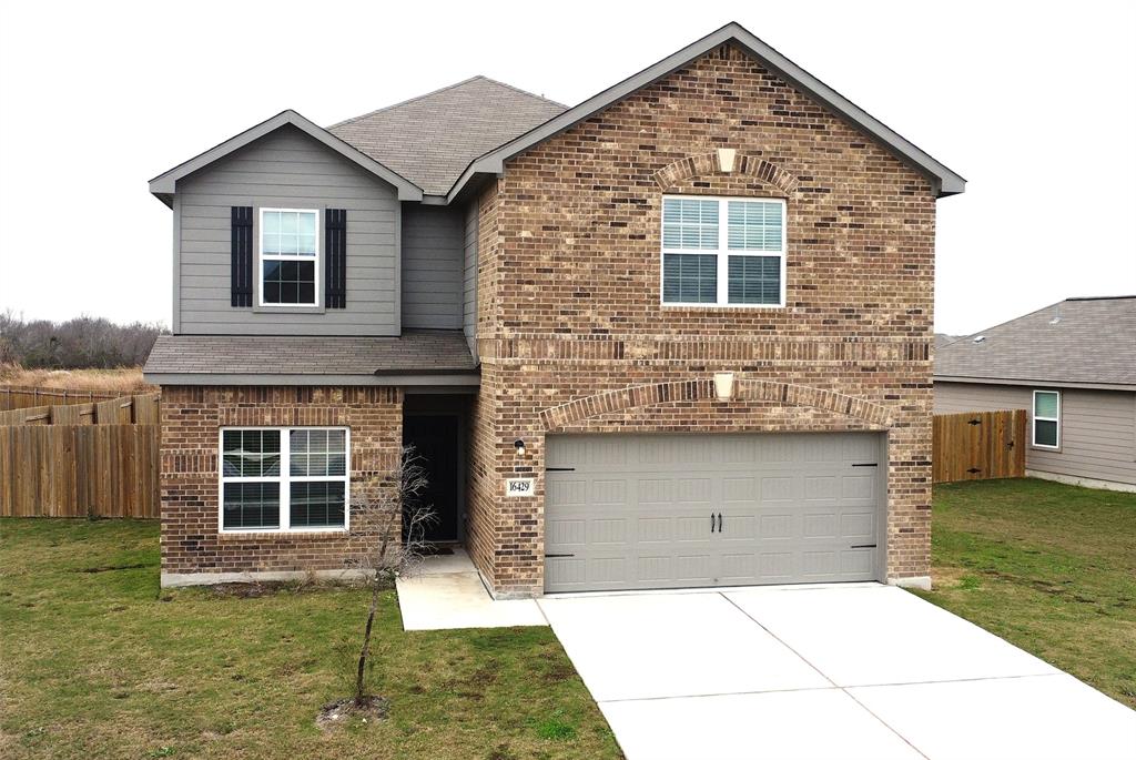 16429 Farmhouse Lane Elgin, TX 78621 - Photo 1 of 22 Traditional brick exterior featuring gray siding accents, an attached garage, and a concrete driveway