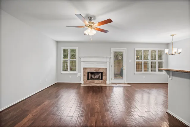 a view of a livingroom with a fireplace a ceiling fan and wooden floor