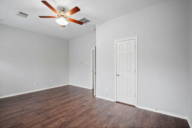an empty room with wooden floor and a ceiling fan