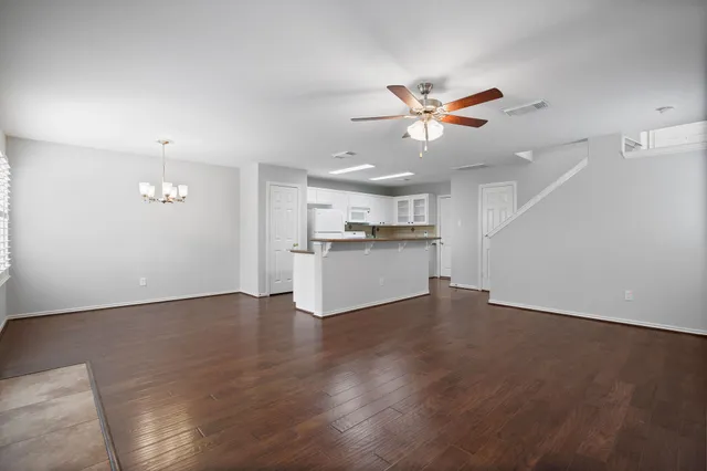 a view of a kitchen with a dishwasher a kitchen island wooden floor and a ceiling fan