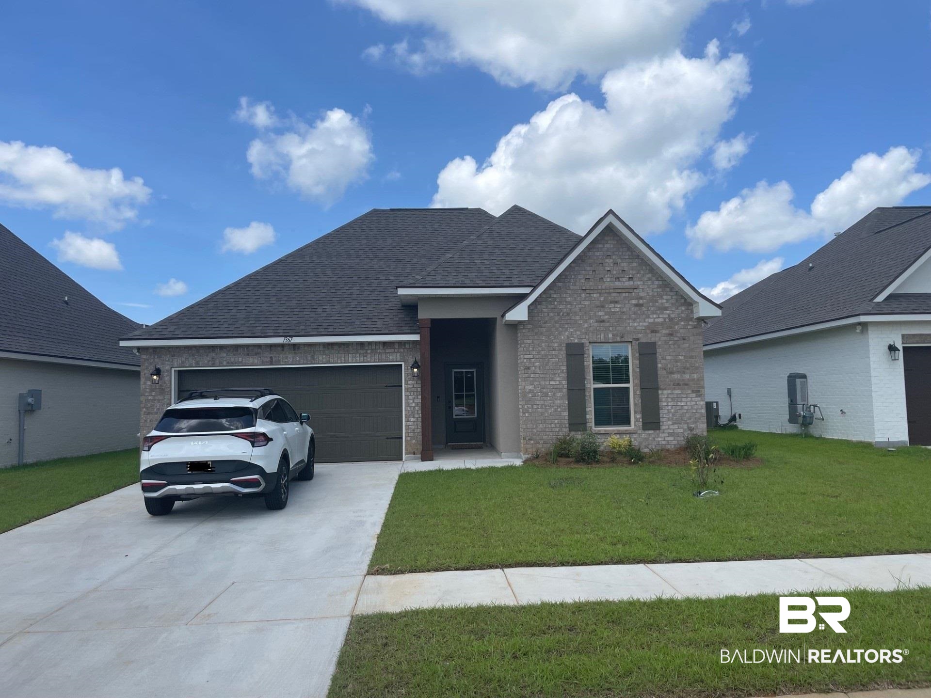 1367 Fenton Circle Foley, AL 36535 - Photo 1 of 3 View of front facade featuring brick siding, an attached garage, a front yard, driveway, and a shingled roof