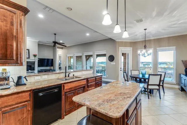 a kitchen with granite countertop center island a sink dishwasher a dining table and chairs with wooden floor