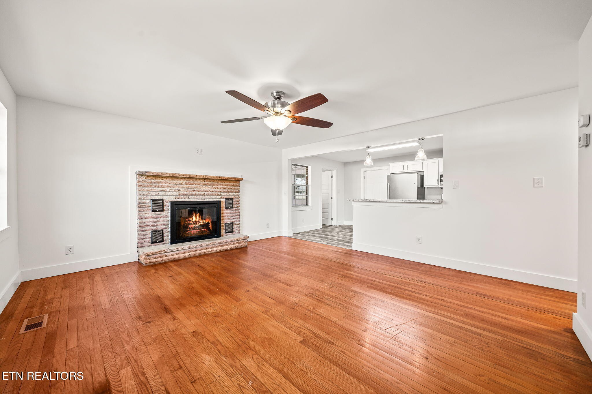 287 Watson Avenue Spring City, TN 37381 - Photo 11 of 24 an empty room with wooden floor a ceiling fan a fireplace and windows