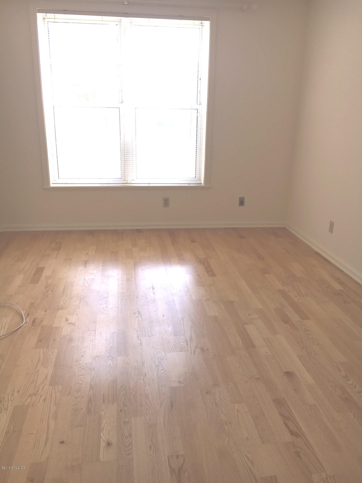 140 Field Point Road, Unit 2 Greenwich, CT 06830 - Photo 9 of 14 an empty room with wooden floor and windows