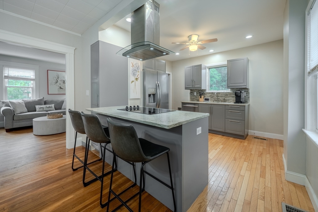 a dining hall with stainless steel appliances granite countertop wooden floor a dining table and chairs