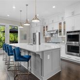 a kitchen with stainless steel appliances granite countertop a stove a refrigerator a kitchen island a table and chairs with wooden floor