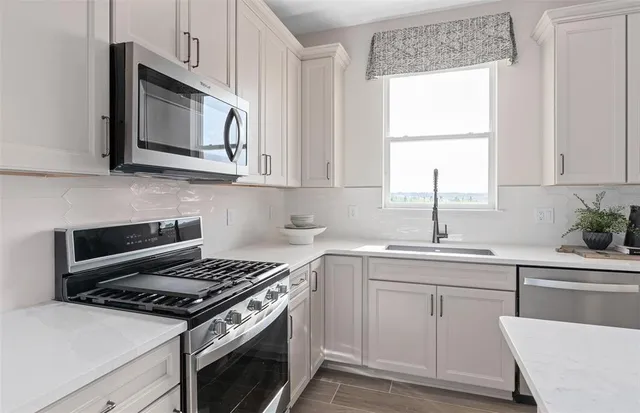 a kitchen with cabinets appliances a sink and a window