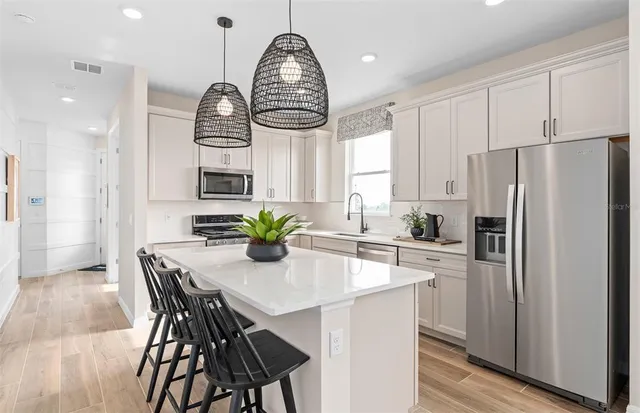 a kitchen with stainless steel appliances a dining table chairs and wooden floor