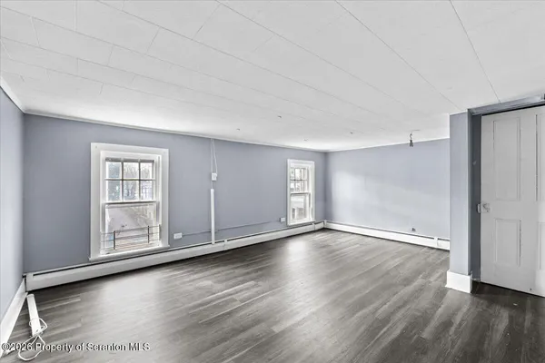 an empty room with wooden floor and window