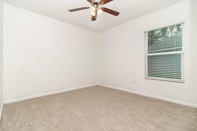 an empty room with window and ceiling fan