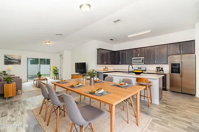 a dining room with stainless steel appliances kitchen island granite countertop a dining table and chairs