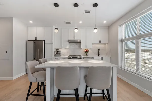 a kitchen with stainless steel appliances granite countertop a table chairs stove and refrigerator