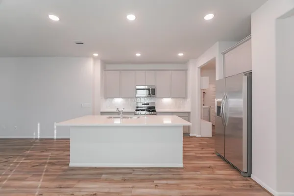 a large kitchen with stainless steel appliances granite countertop a large counter top a stove and a refrigerator