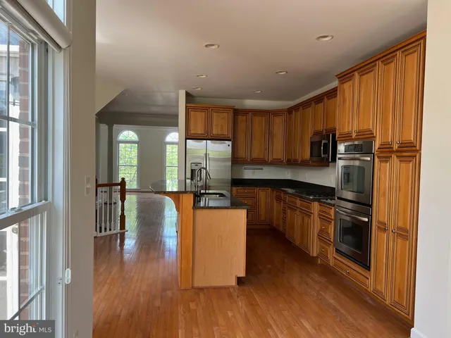 a kitchen with stainless steel appliances granite countertop a refrigerator a stove a sink and a granite counter tops with wooden floors