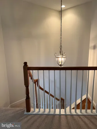 a view of staircase with railing and a chandelier