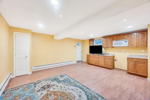 a view of a kitchen with kitchen island wooden floor and stainless steel appliances