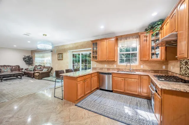 a kitchen with stainless steel appliances granite countertop a stove top oven a sink dishwasher and cabinets with wooden floor