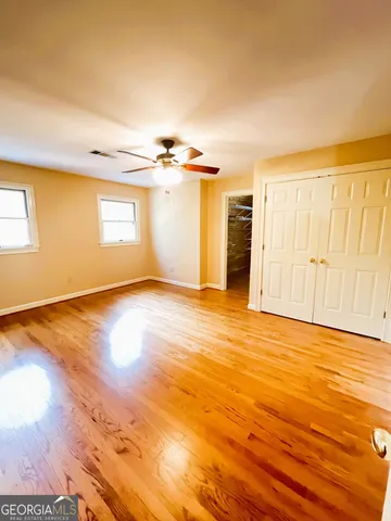 a view of an empty room with a window and wooden floor