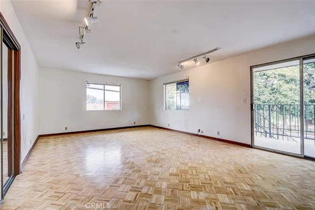 a view of an empty room with window and wooden floor