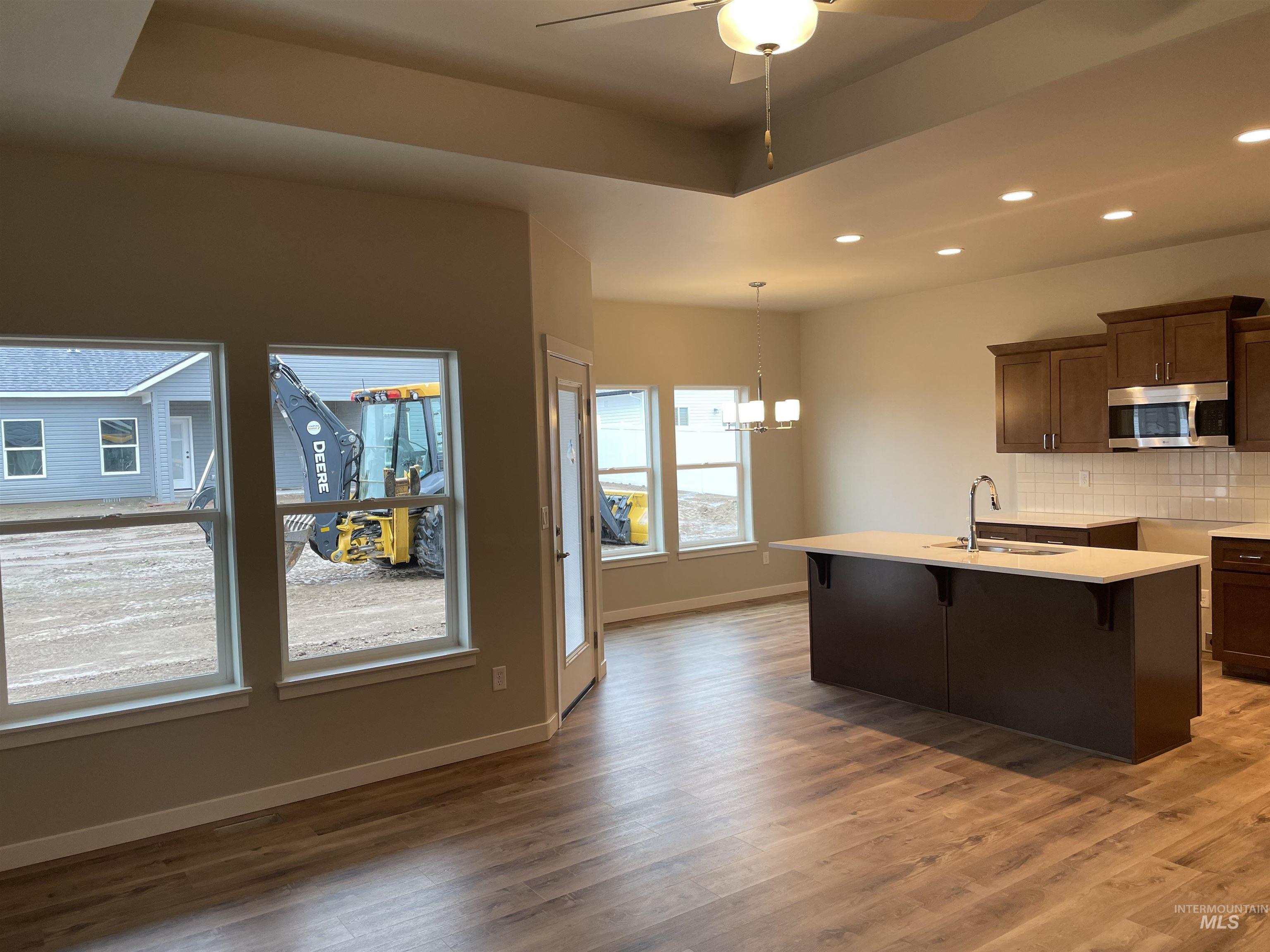 1123 Frank Henry Road Twin Falls, ID 83301 - Photo 3 of 20 Kitchen with a kitchen bar, dark wood finish cabinets, backsplash, suspended lighting, and stainless steel microwave